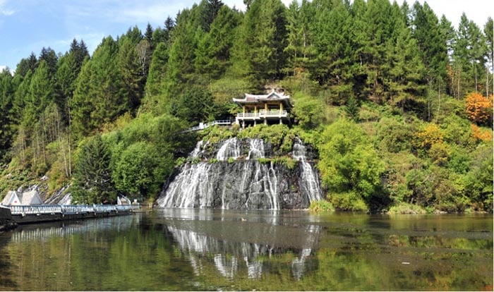 Traditional Korean pavilion amid cascading waterfalls and lush forest