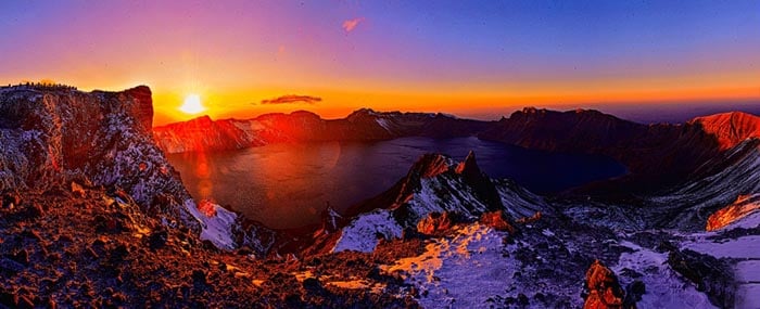 Panoramic sunset over Mount Paektu crater with golden and purple skies